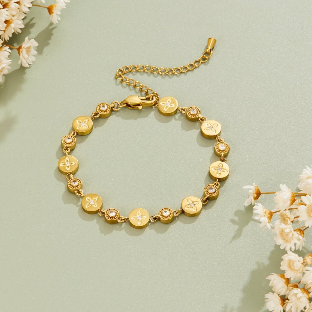 Spring Bloom Gold Bracelet, laid flat on sage green with dried white flowers around it