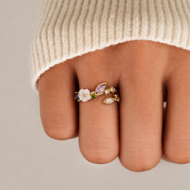 Crystal White Blossom Ring Gold, worn on a hand with a cream knit sleeve, close-up
